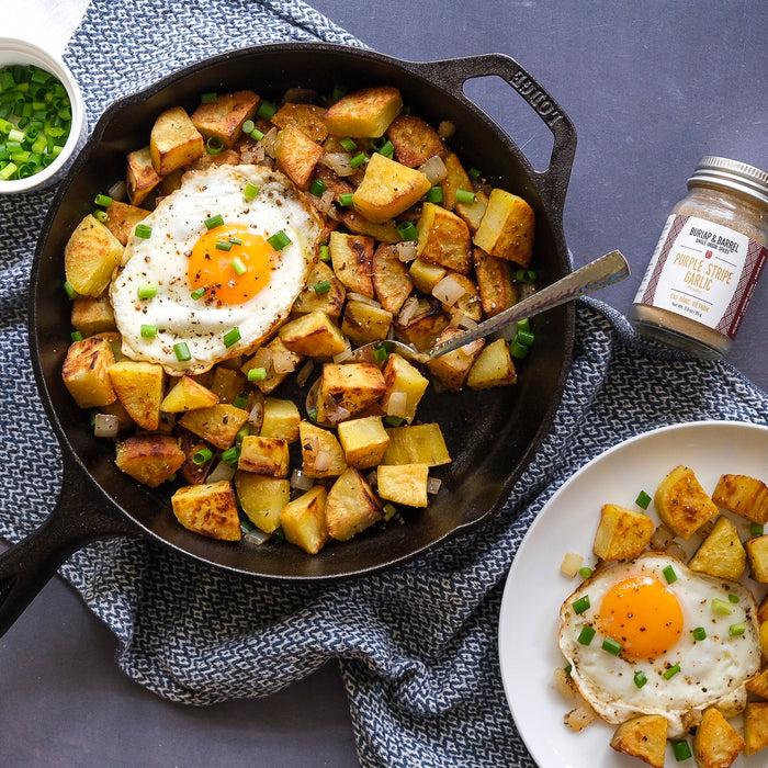 Skillet with potato hash and fried egg with purple stripe garlic from Burlap & Barrel