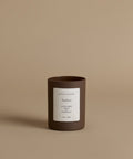 A glass candle with the scent Amber against a beige background.