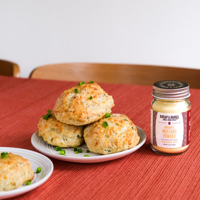 Biscuits on a plate with a jar of mustard powder on a red tablecloth