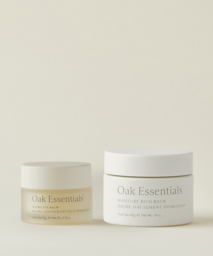 The Best-Selling Balm Duo by Oak Essentials features sleek, minimalist jars with white lids—a small Hydra Eye Balm for under eyes and a larger Moisture Rich Balm—both designed for all-over hydration on a neutral background.