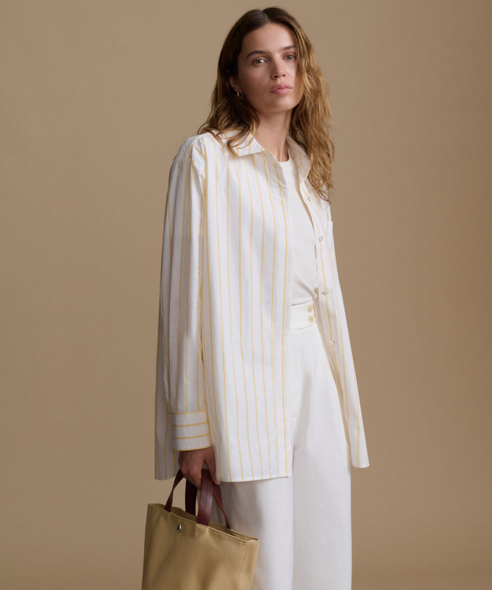 Woman wearing a white and yellow striped shirt with a beige background