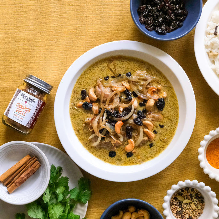 bowl of soup with garnishes on a yellow tablecloth and cinnamon quills in a jar
