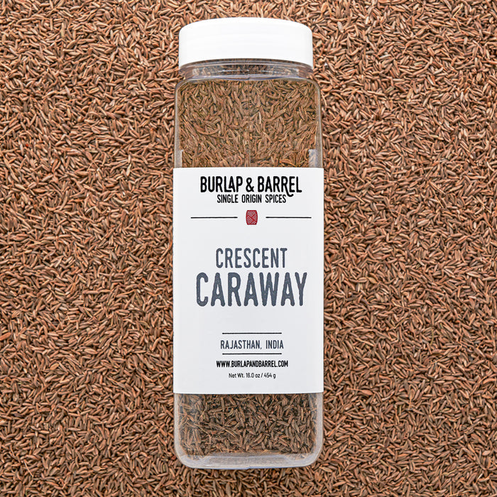 Bottle of Burlap & Barrel Crescent Caraway on a caraway seed background from Burlap & Barrel