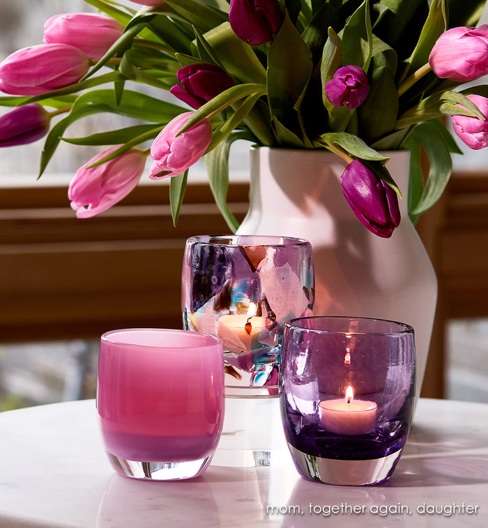 mom, together again, daughter Pink and purple glass candle holders  with a vase of pink tulips on a table.