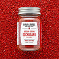 Jar of Burlap & Barrel Gochugaru chili flakes on a red background