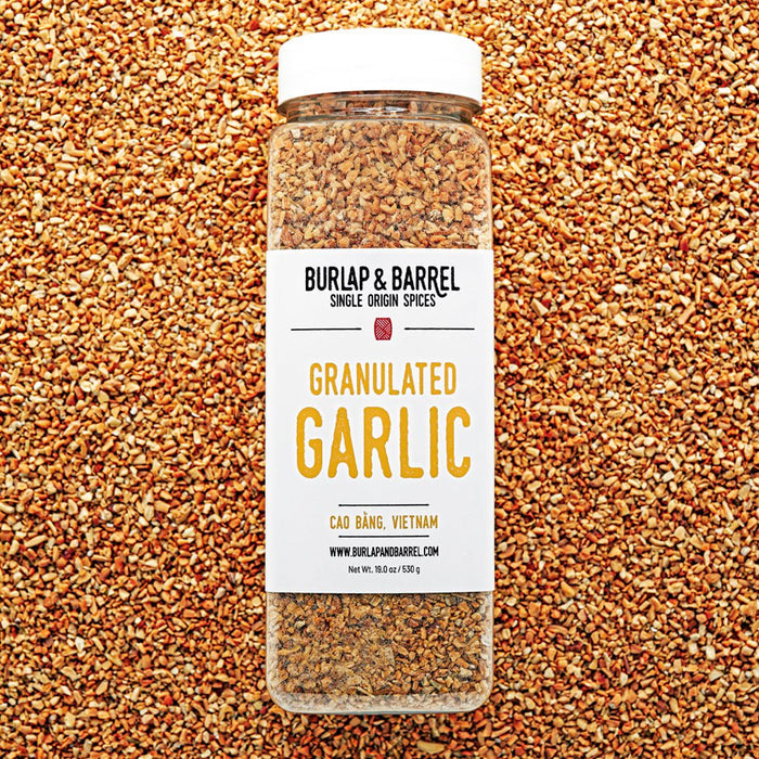 Jar of granulated garlic from Burlap & Barrel on a bed of granulated garlic.