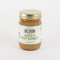 A jar of Big Spoon Roasters Hatch Hot Honey in garlic butter flavor, featuring a white label with green text and a gold metal lid, set against a plain white background.