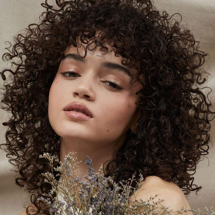 Tea Tree female model with curly haired finish look in lifestyle setting