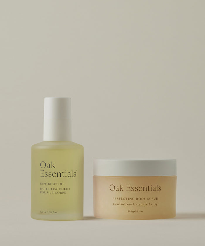 The Lymphatic Massage Set by Oak Essentials is shown on a neutral background, featuring Dew Body Oil in a frosted pump bottle and Perfecting Body Scrub in a round jar—perfect for your daily massage ritual.