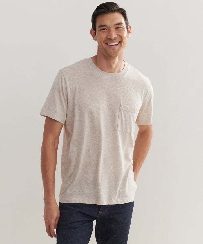 A man wearing the Mens Vintage Pocket Tee and dark jeans stands smiling with one hand in his pocket against a plain, light background.