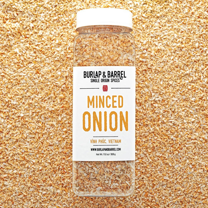 Jar of minced onion spice with Burlap & Barrel label on a textured gold background