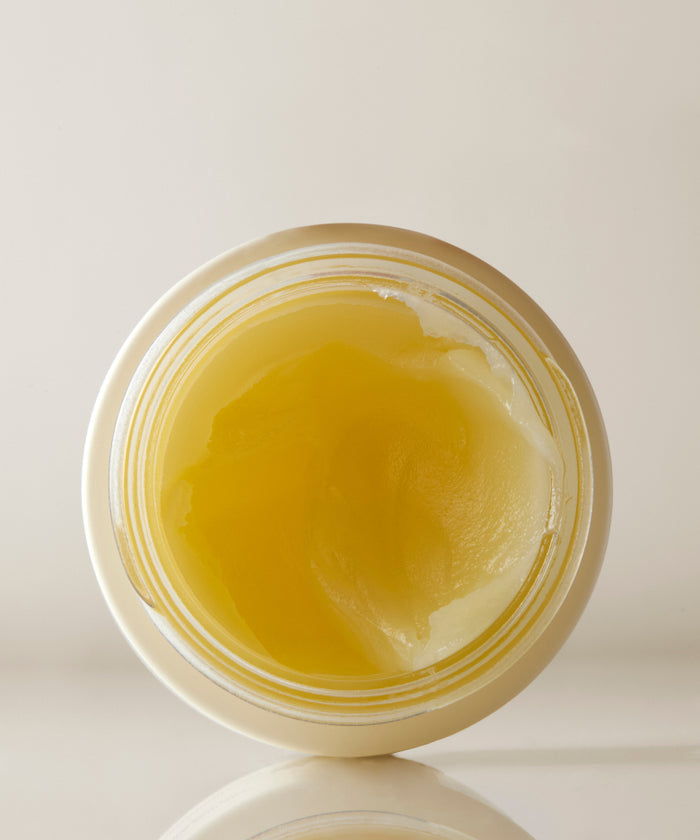 A top-down view of an open jar of Moisture Rich Balm reveals its yellowish, semi-solid texture with Sea Buckthorn Oil against a plain light background.