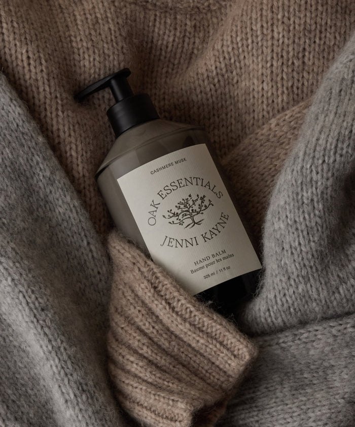 Hand balm bottle with Jenni Kayne branding on a knitted fabric background