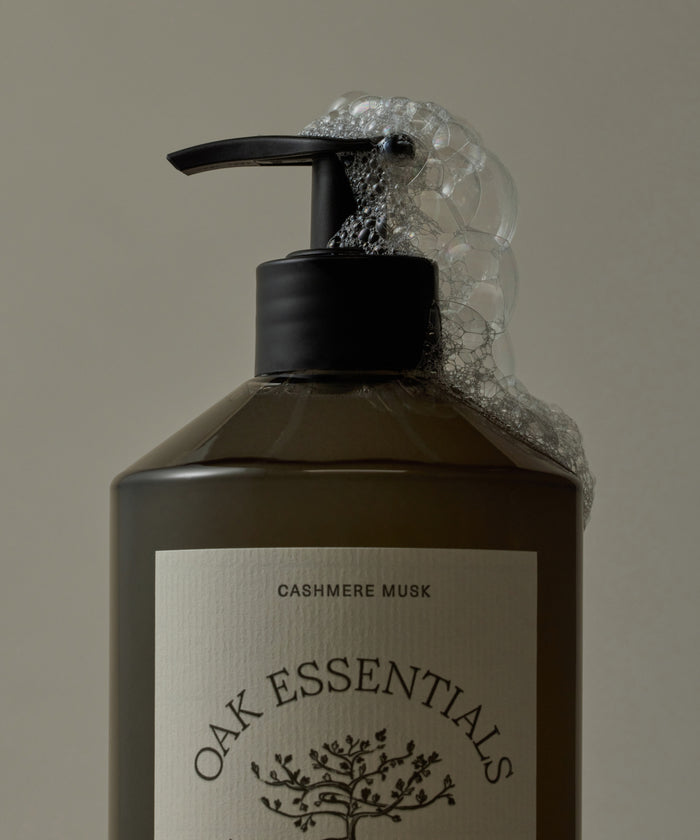 Bottle of Oak Essentials Cashmere Musk soap with a pump and visible label on a beige background