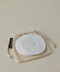 A set of round, white Reusable Cotton Rounds is neatly arranged on a washable cotton mesh bag labeled Oat Essentials, ideal for enhancing your cleansing routine against a light neutral background.