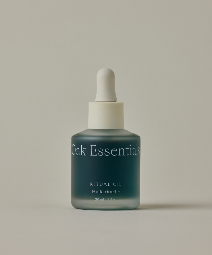 A frosted glass bottle labeled "Ritual Oil" with a white dropper cap, designed for sensitive skin, is set against a plain beige background.