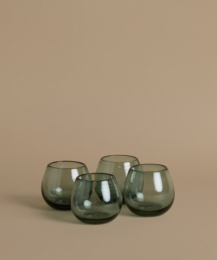 Recycled glass cups against a beige background.