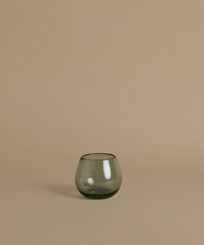 Recycled glass cup against a beige background.