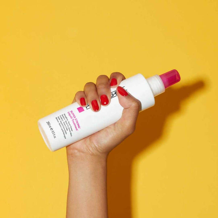 Image of Paul Mitchell Super Strong Liquid Treatment being held in front of a yellow background