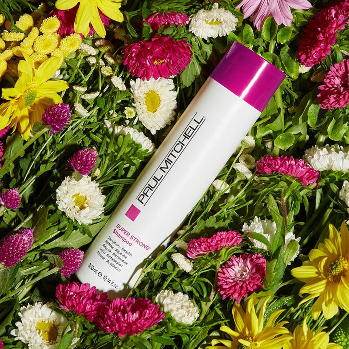An artistic / lifestyle image of Paul Mitchell Super Strong Shampoo laying in a bed of flowers