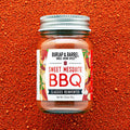 Jar of Burlap & Barrel Sweet Mesquite BBQ spice blend on a red background