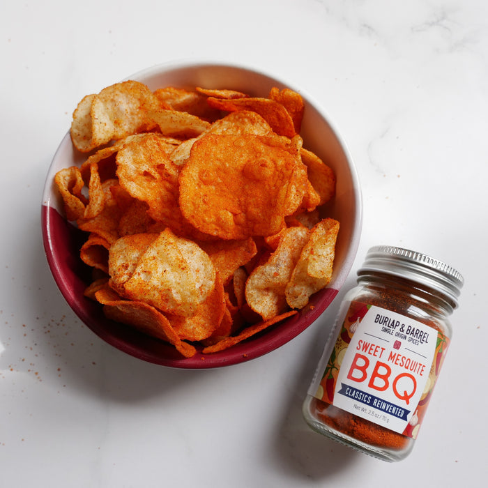 bowl of chips with a jar of Sweet Mesquite BBQ seasoning on a white surface