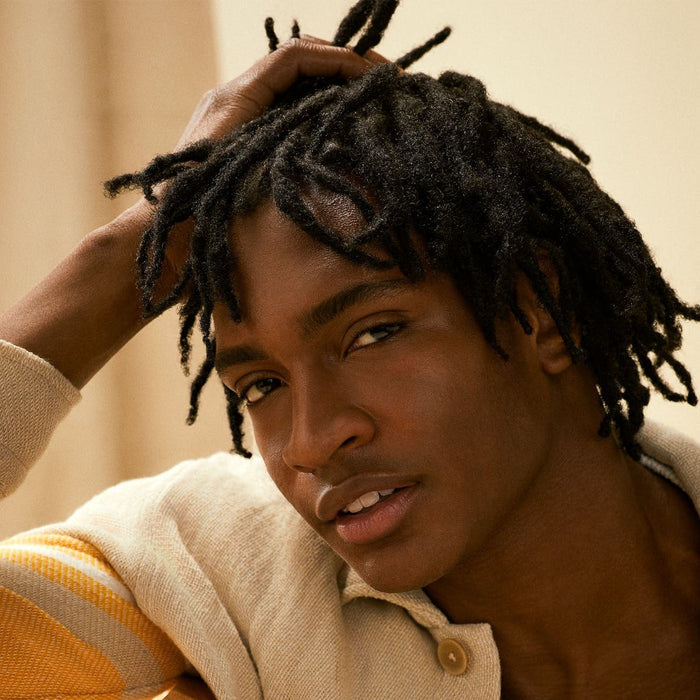 Tea Tree Scalp Wellness Dry Scalp Serum male model holding their hair / head.