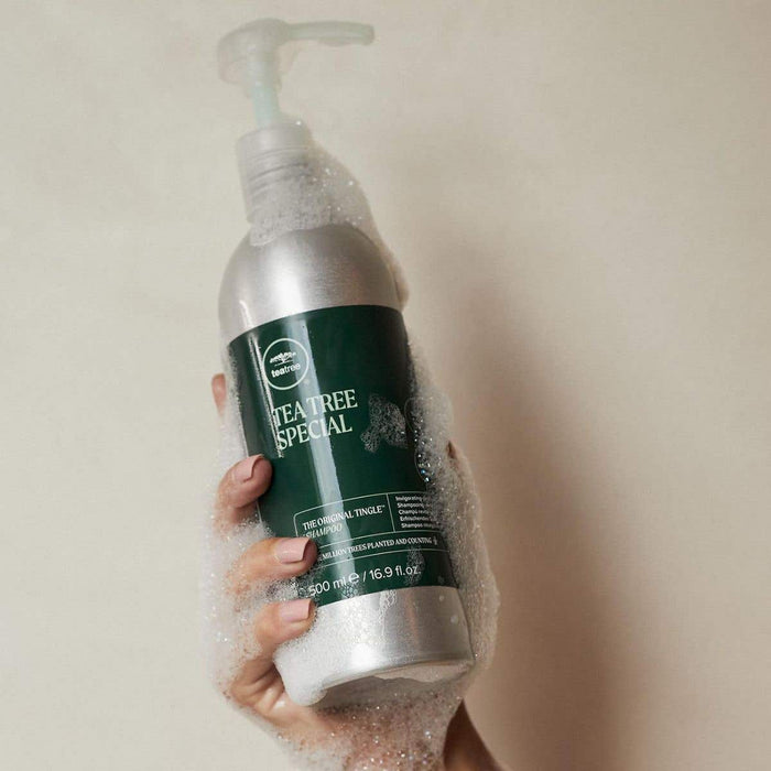 Image of someone holding Tea Tree Special Shampoo Aluminum Bottle with suds all over it