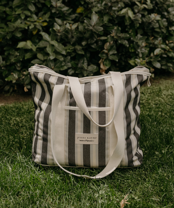 Striped tote bag with visible brand name on grass