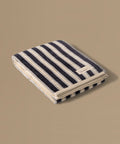 Folded striped towel with a brand label on a beige background