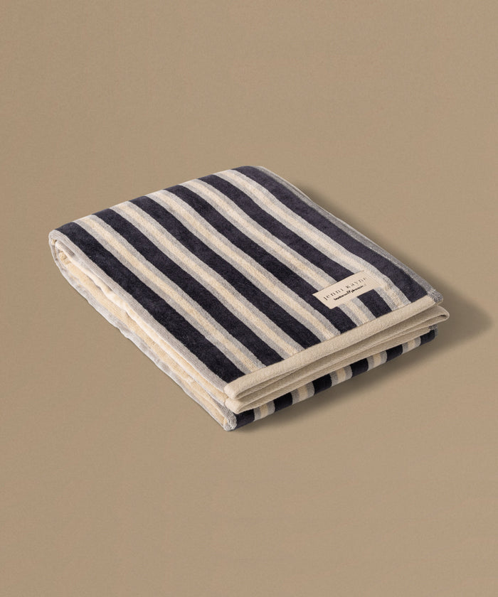 Folded striped towel with a brand label on a beige background