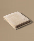 Folded beige towel with a brand label on a beige background