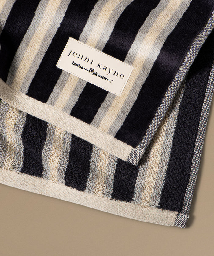 Striped towel with a Jenni Kayne label on a beige background