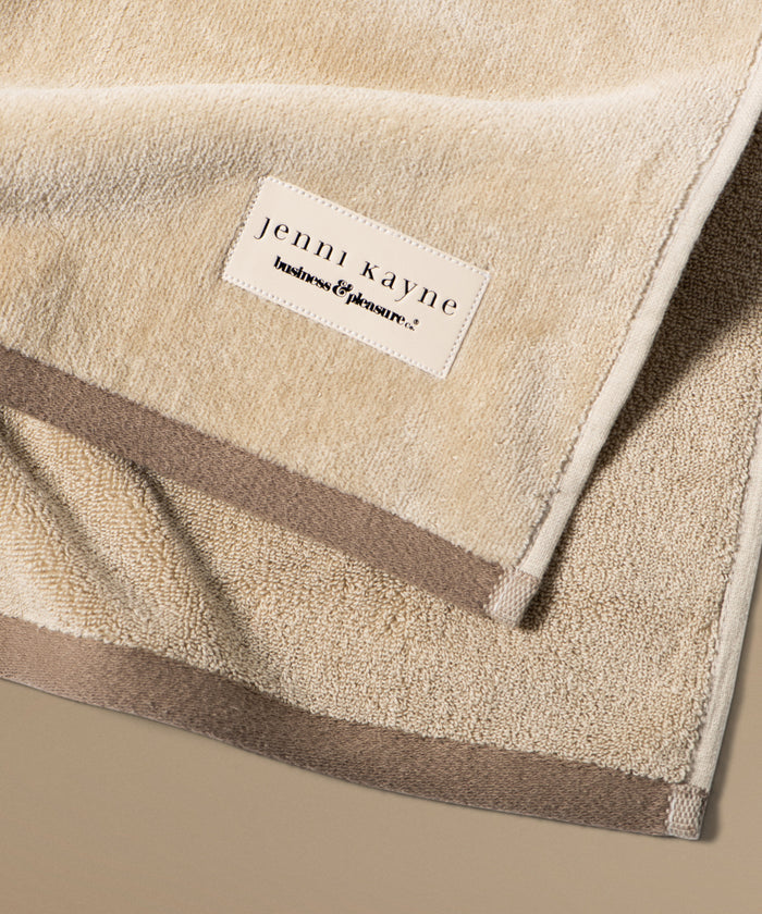 Beige towel with 'jenni kayne' label on a beige background