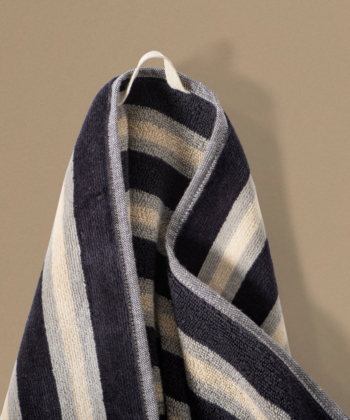 Striped towel with blue, beige, and white colors on a plain background