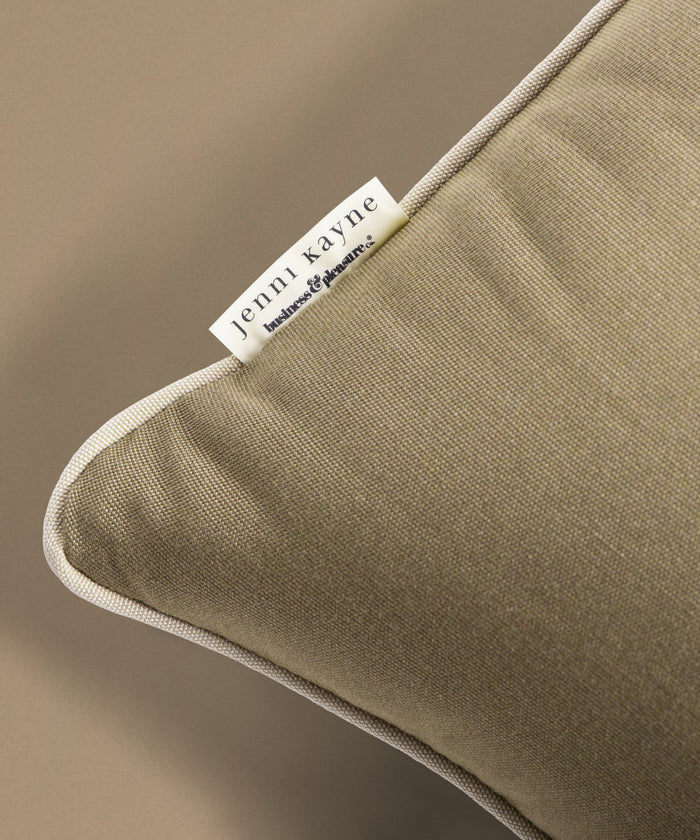 Close-up of a brown pillow with a Jenni Kayne label on a beige background