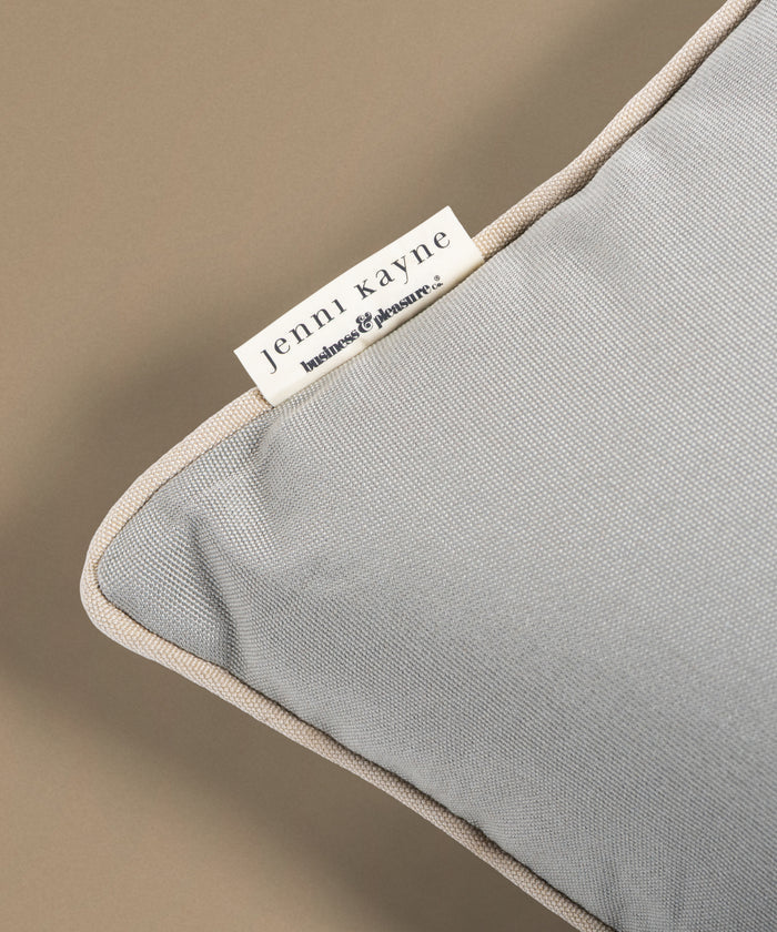 Gray pillow with beige trim and Jenni Kayne label on a beige background