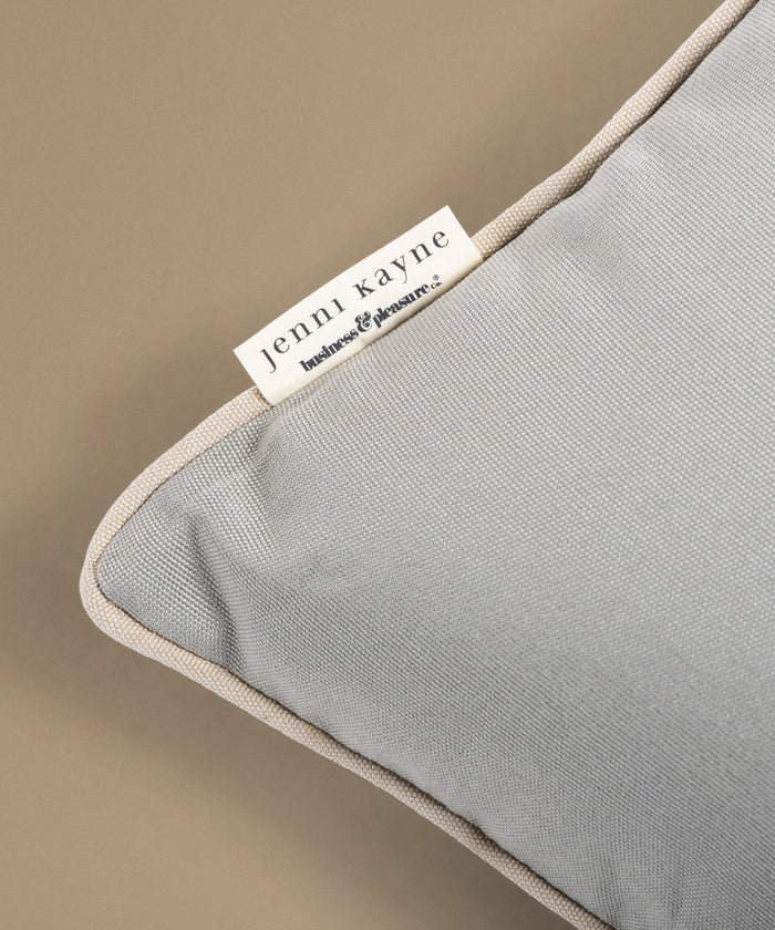 Gray pillow with a Jenni Kayne label on a beige background
